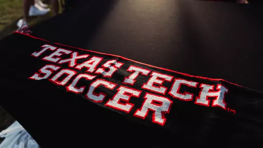 A Texas Tech soccer scarf with white font and red outlining on a black table