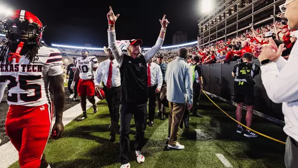 Joey McGuire raises both arms up to signal "Guns Up" to the Texas Tech fans in attendance after the Red Raiders defeated Colorado in Boulder.