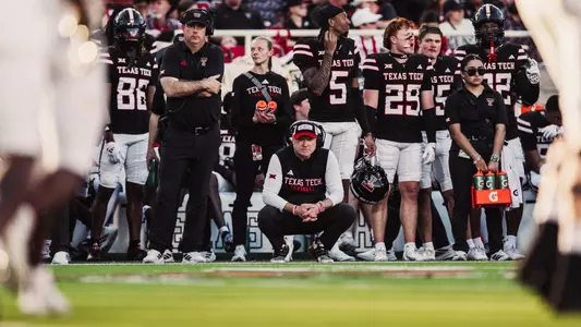 Joey McGuire kneels down on the sidelines to watch a play during Texas Tech's 2025 victory over UCF.