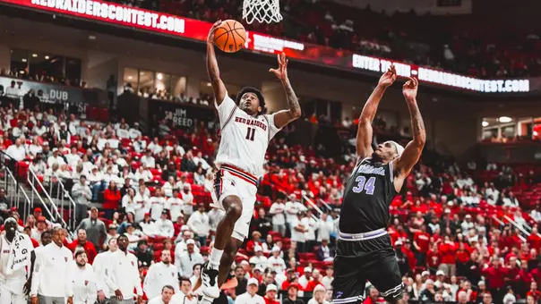 Jaylen Petty goes up for a dunk with a Kansas State defender closing in.