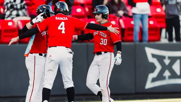 Texas Tech OF Jesse Rusinek wearing the Red Raiders red uniforms is greeted by teammates Linkin Garcia (4) and Matt Quintanar (26) after launching his first home run of his career on Saturday afternoon