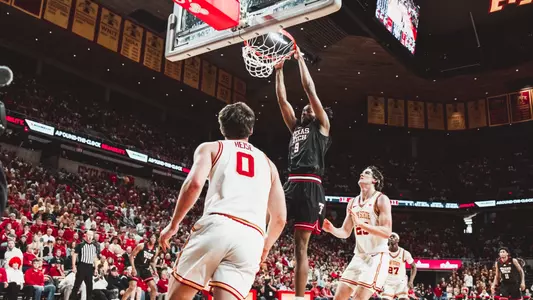 Luke Bamgboye throws down a dunk with two Iowa State defenders around him.