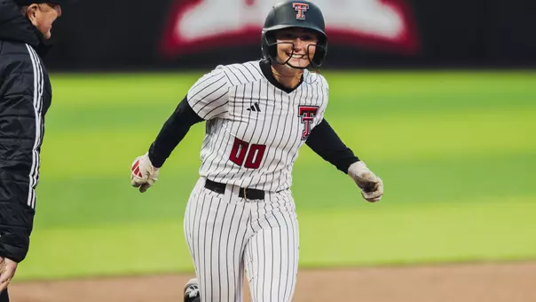Jackie Lis smiles with coach Gerry Glasco while rounding third base after hitting a home run