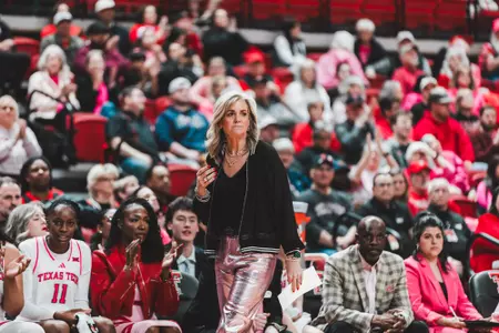 Head Coach Krista Gerlich stands on the sideline in front of the Texas Tech bench and watches the team score.