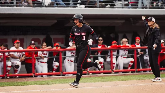 Lauren Allred heading to home plate after a hitting a home run and celebrating with coach Tara Archibald in the background