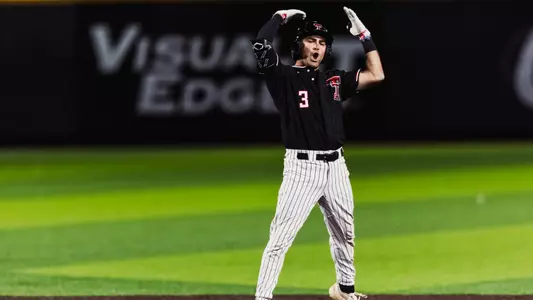 Texas Tech Senior infielder Tracer Lopez raises his hands over his head in jubilation following his seventh inning two-run double, his 200th career hit as a Red Raider