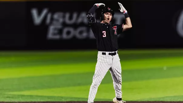 Texas Tech Senior infielder Tracer Lopez raises his hands over his head in jubilation following his seventh inning two-run double, his 200th career hit as a Red Raider