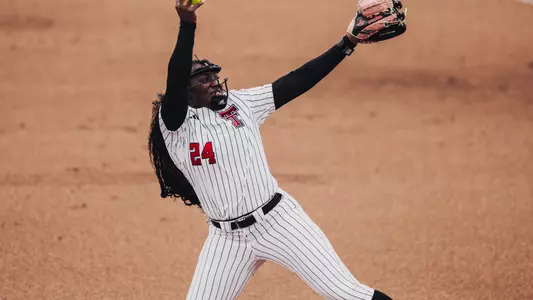 NiJaree Canady throwing a pitch in a white pinstripe jersey with a pink glove