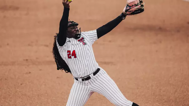 NiJaree Canady throwing a pitch in a white pinstripe jersey with a pink glove