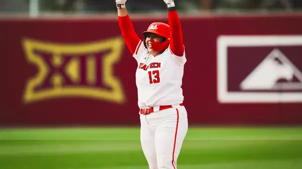 Victoria Valdez standing on second base celebrating a hit with her hands raised in the air