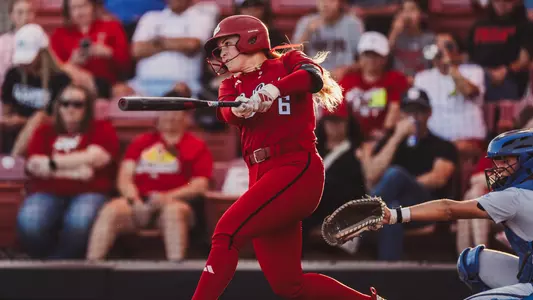 Taylor Pannell swining her bat against BYU in an all-red uniform