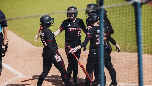 The softball team celebrating at home plate after a home run by Taylro Pannell