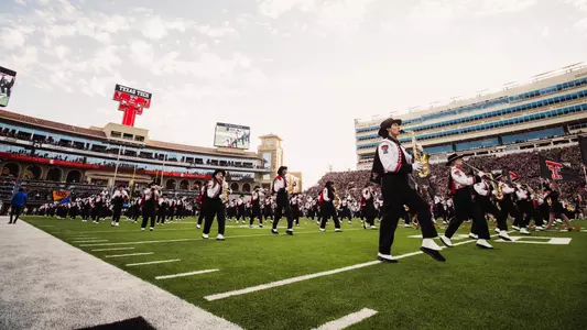 The Goin' Band from Raiderland takes the Jones AT&T Stadium field with the South End Zone Building in the background.