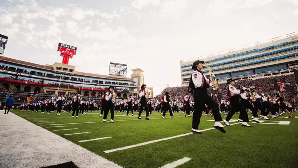 The Goin' Band from Raiderland takes the Jones AT&T Stadium field with the South End Zone Building in the background.