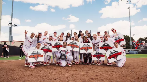 Texas Tech softball team celebrating winning the Big 12 by taking a team picture infornt of the trophy at Tracy Sellers Field