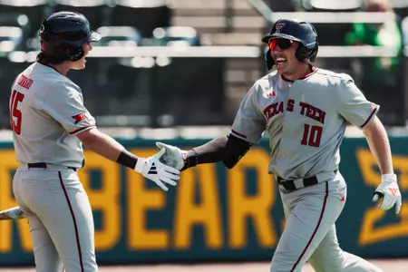 Logan Hughes High-Fives teammate Caden Ferraro after launching a home run at Baylor
