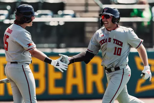 Logan Hughes High-Fives teammate Caden Ferraro after launching a home run at Baylor