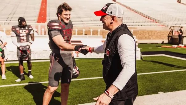 Joey McGuire and Ben Roberts share a laugh and handshake during Texas Tech's annual Spring Game inside Jones AT&T Stadium.