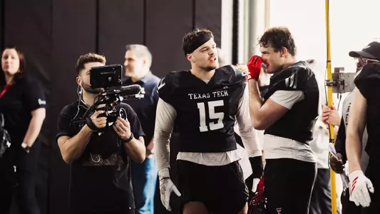 Austin Romaine and Ben Roberts speak on the sideline during one of Texas Tech's spring practices as a Paramount+ camera operator captures the converstation.