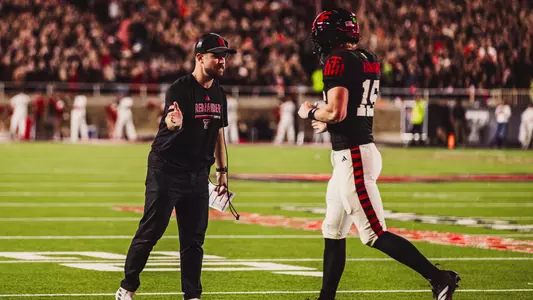 Will Hammond is greeted coming off the field by offensive coordinator Mack Leftwich during Texas Tech's 2025 win over Kansas.