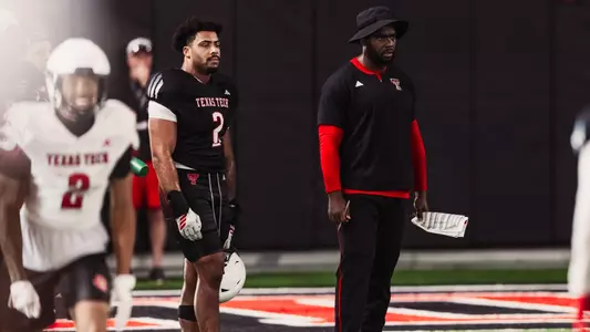 Jacquies Smith standing with Trey White as they watch Texas Tech fall camp