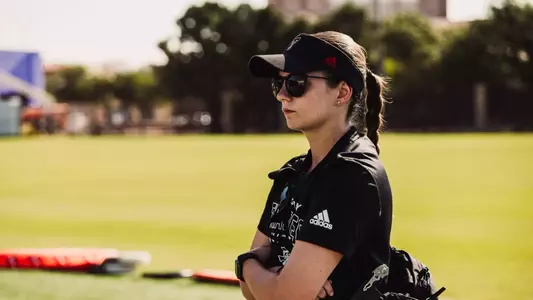 Erika Rowe standing with crossed arms at the outdoor football practice field