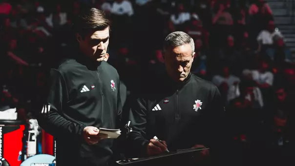 Grant McCasland and Brian Pete look over some plays before the start of a NCAA Tournament game.