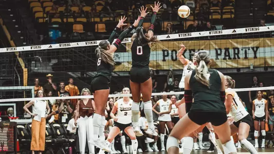 Kenna McKenzie and Faith Jordan jumping up to block a ball