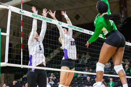 Addie Schmotzer and Tezra Rudzitis jump at the net to attempt a block
