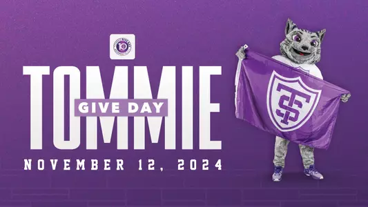 Tommie mascot holds a St. Thomas shield flag next to text that reads Tommie Give Day November 12, 2024