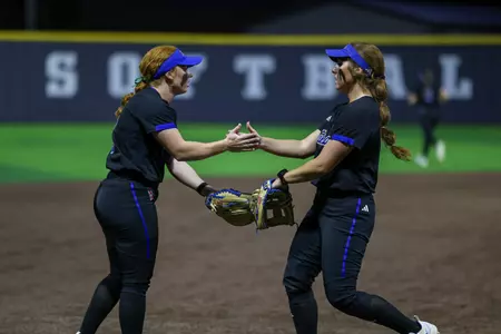 Maci Cole and Claira Skaggs hi-five in the field at Tarleton State
