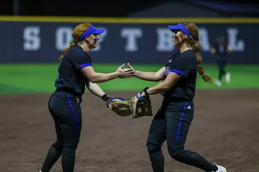 Maci Cole and Claira Skaggs hi-five in the field at Tarleton State