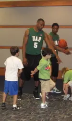 UAB men's basketball players Robert Williams (#5) and Quincy Taylor show children at the McWane Center some exercises.