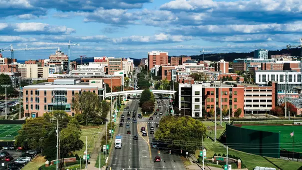 Drone photo over University Boulevard looking East across the center of campus with blue sky and white clouds above, October 2023.