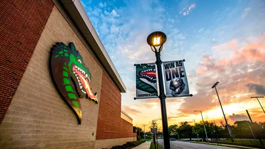 Detail of lighted "Blaze" head signage on an exterior wall of the UAB Football Operations Center with the sky at sunset in the background, April 2020.