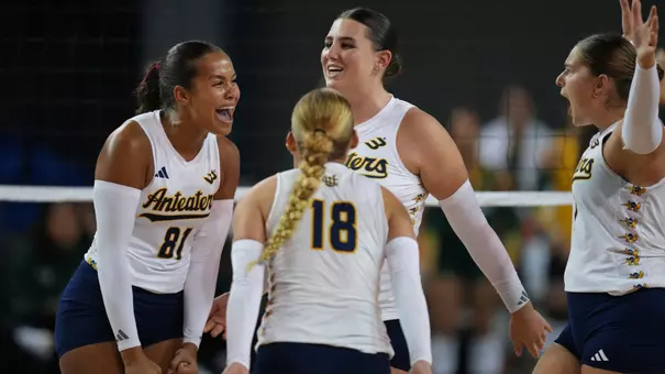 UCI women's volleyball players Memphis Burnett, Taylor Boice, and Nicole Feliciano celebrate on the court after winning a point.