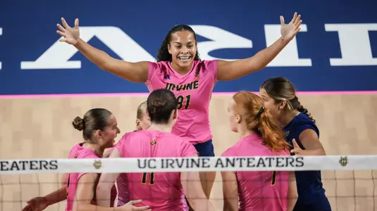 Memphis Burnett raises both arms as she celebrates a point with her teammates in an NCAA women's volleyball match.
