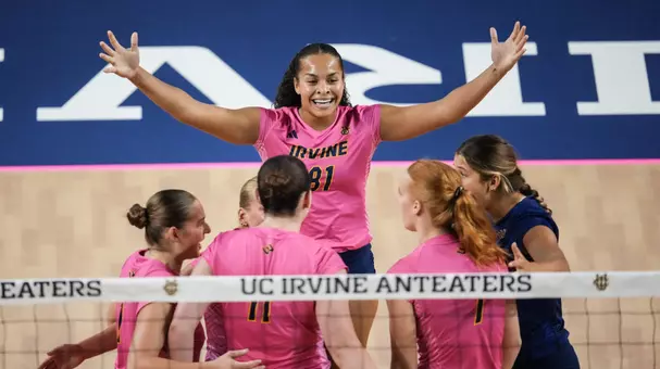 Memphis Burnett raises both arms as she celebrates a point with her teammates in an NCAA women's volleyball match.