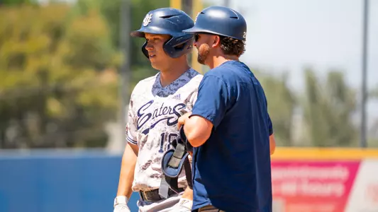 Zach Crandall stands on first base with assistant coach Ryan Johnston in a game at UC Riverside