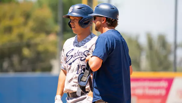 Zach Crandall stands on first base with assistant coach Ryan Johnston in a game at UC Riverside