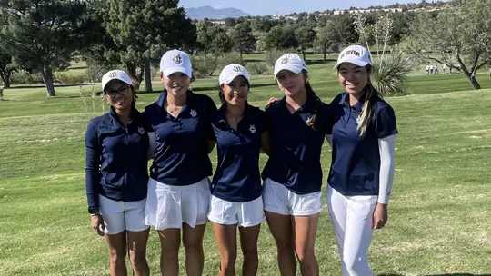 Five UC Irvine women's golfers pose for a photo side-by-side on the course