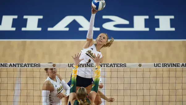 Photo of Abby Pekrul making contact with the ball above the net on a middle attack.