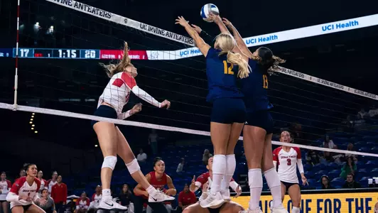 Madison Triplett and Vani Tatoulian in blue uniforms go up for a double block in an NCAA Women's Volleyball match against Utah Tech.