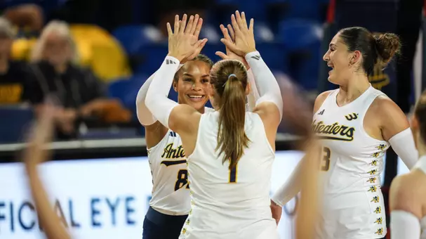 Memphis Burnett high fives Nicole Feliciano after winning a point in an NCAA women's volleyball match.