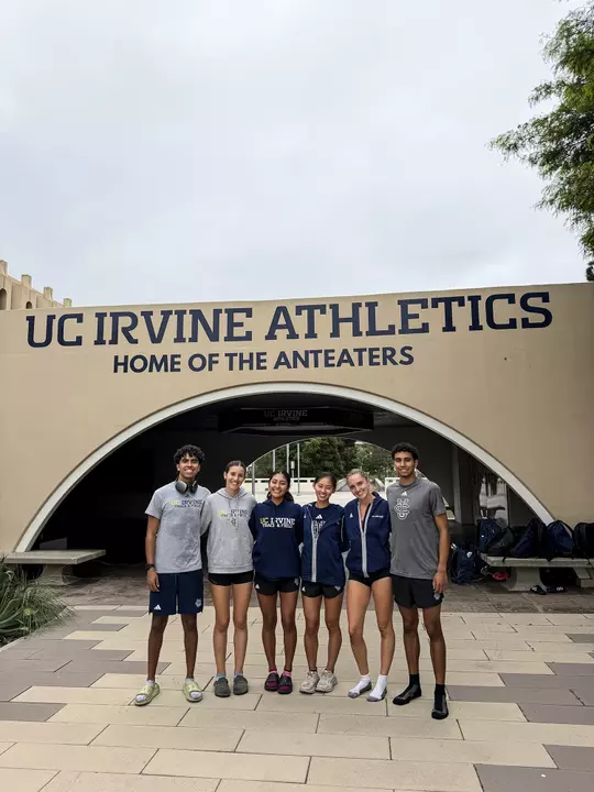 Six members of the UCI men's and women's cross country team pose in front of the arch at Crawford.