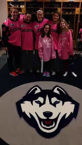 UConn players pose in the locker room with clinic participants