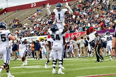 Christian Haynes and Keelan Marion celebrate after the Huskies scored a touchdown against UMass