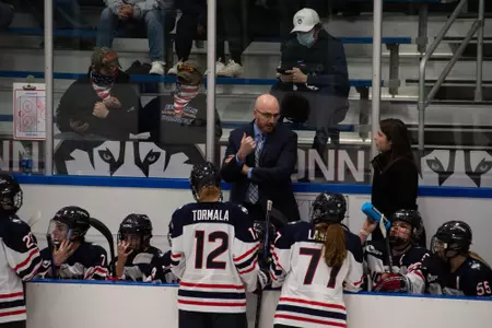 Coaches talk behind the bench during the game against Boston University