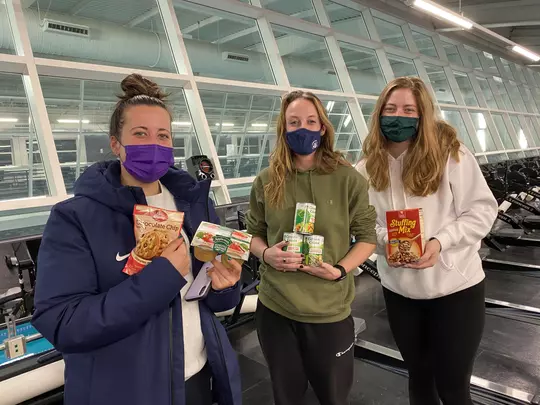 Members of the women's rowing team posing with items they donated towards a food bank