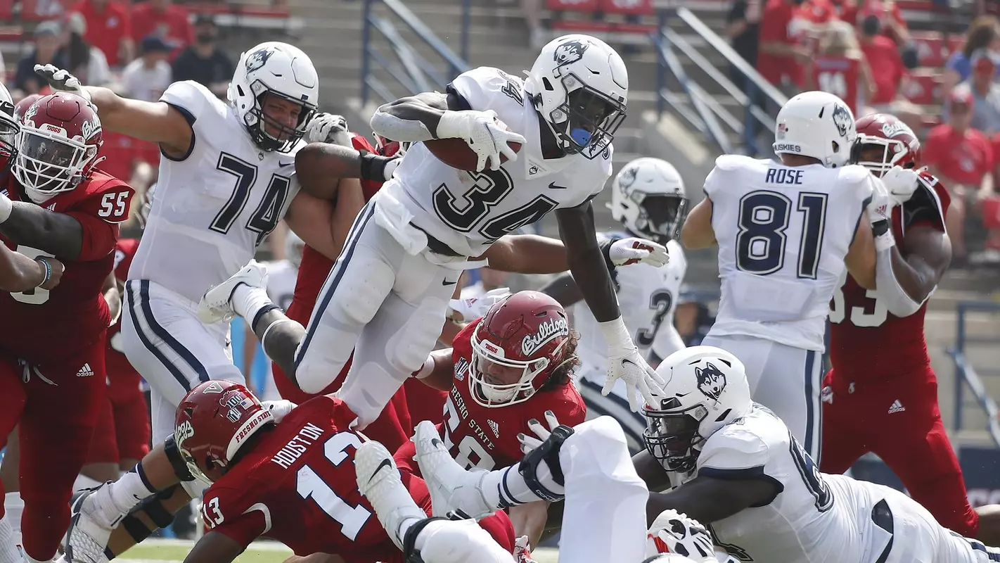Connecticut running back Kevin Mensah goes up high for a short gain against Fresno State during the first half of an NCAA college football game in Fresno, Calif., Saturday, Aug. 28, 2021. (AP Photo/Gary Kazanjian)